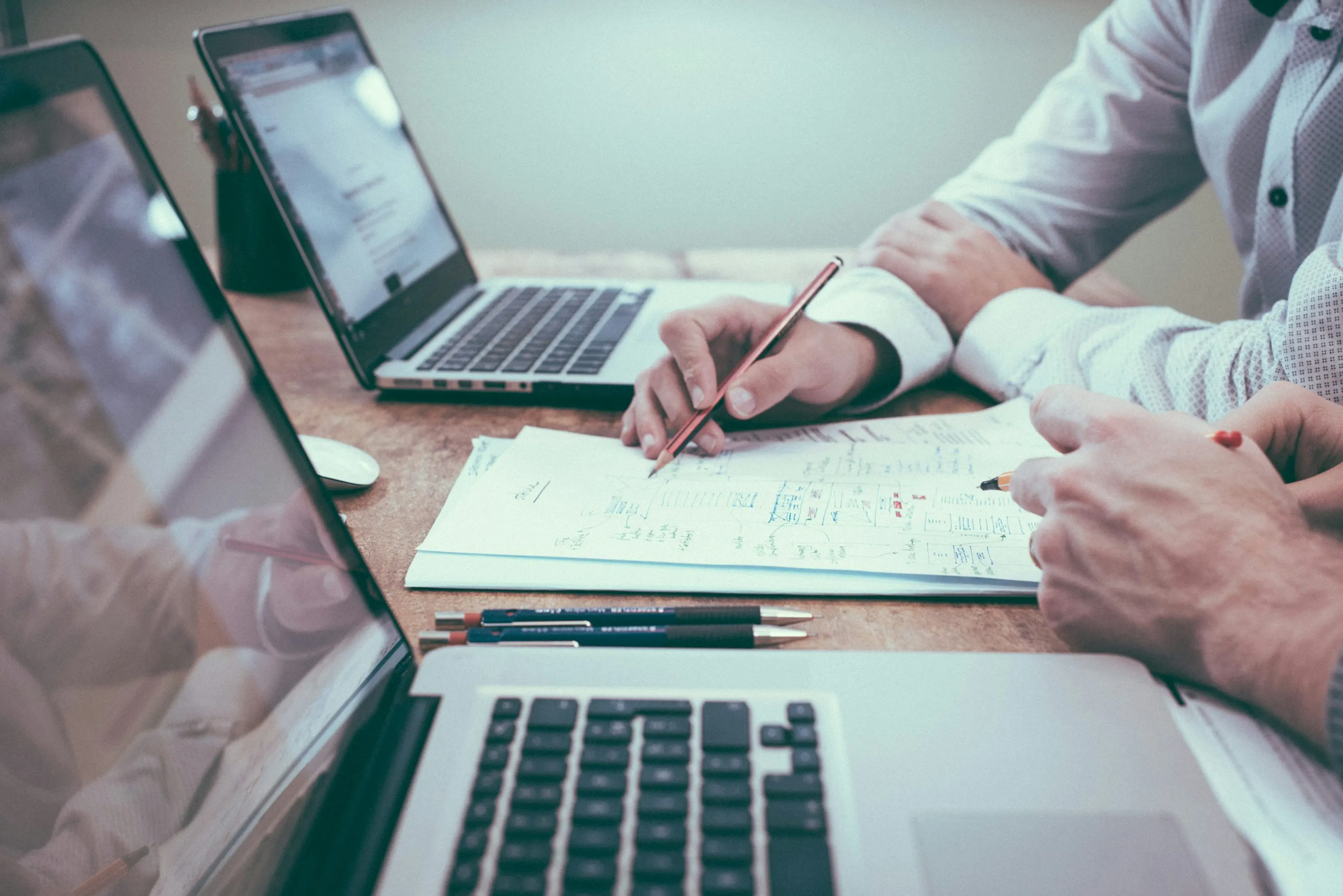 Profesionales revisando notas y planificación comercial junto a varios portátiles