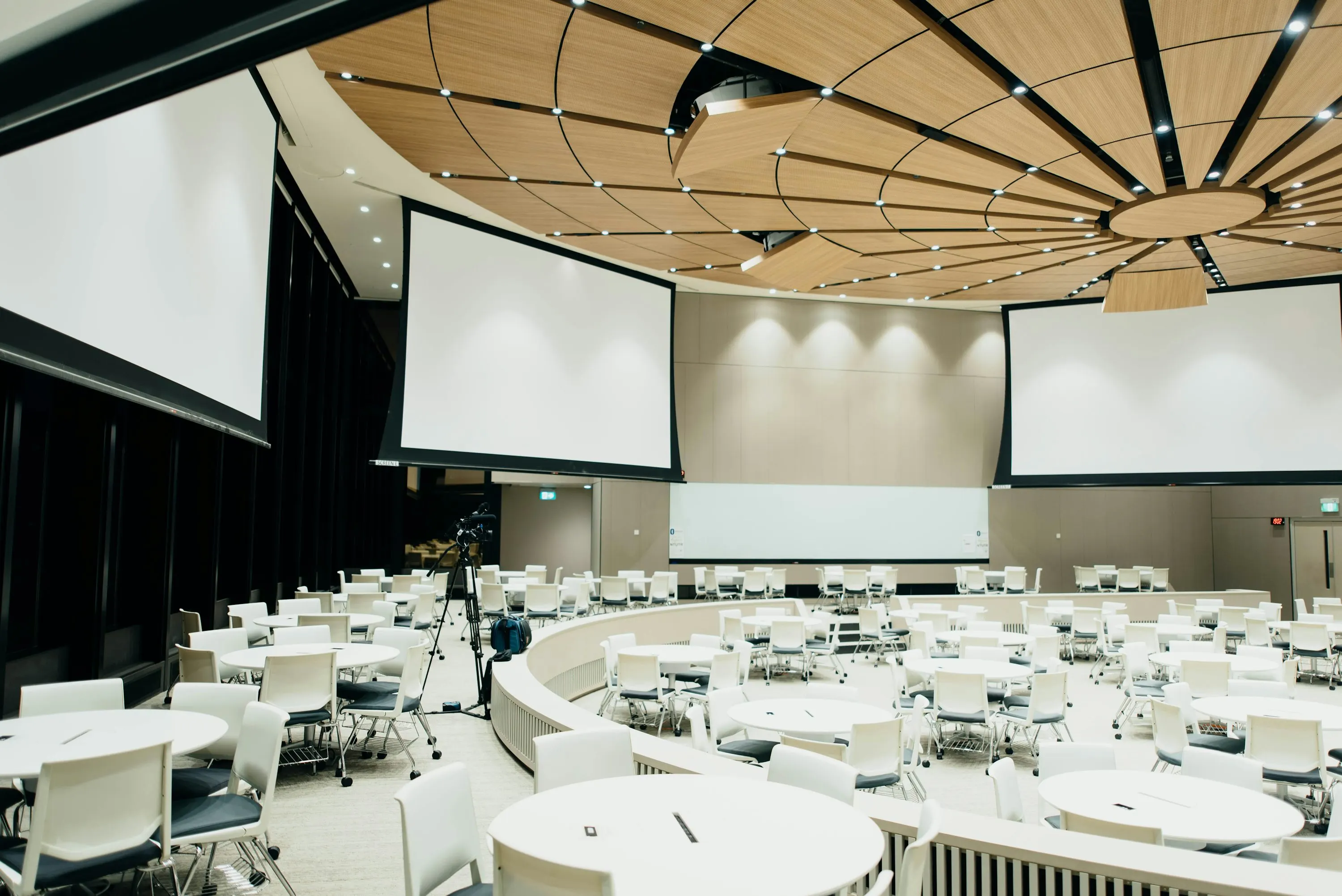 Asistentes en un evento profesional con escenario y ambiente de conferencia